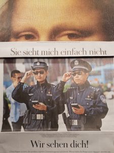Zeitungsausschnitt: Augen der Mona Lisa, darunter steht: "Sie sieht mich einfach nicht" - Darunter aus anderem Zeitungsausschnitt zwei chinesische Polizisten mit Sonnenbrille: "Wir sehen dich!"