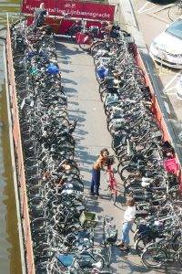 Blick von oben auf einen dicht gefüllten schwimmenden Fahrradparkplatz auf einer Gracht Amsterdams