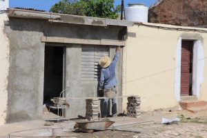 Ein Maurer arbeitet an einem kleinen Haus in Trinidad (Cuba). (Rückenansicht)