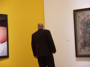Ein Mann (Rückenansicht), links und rechts ein großes Gemälde.