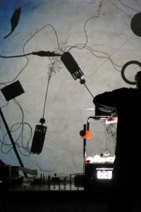 "Overheadbots" werden von einem Tageslichtprojektor in der Nacht an die Wand geworfen. (Ralf Schreiber, Tina Tonagel)