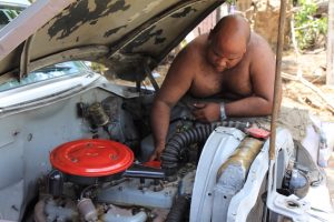 Ein Mann hantiert im Motorraum seines Autos (Santiago de Cuba)